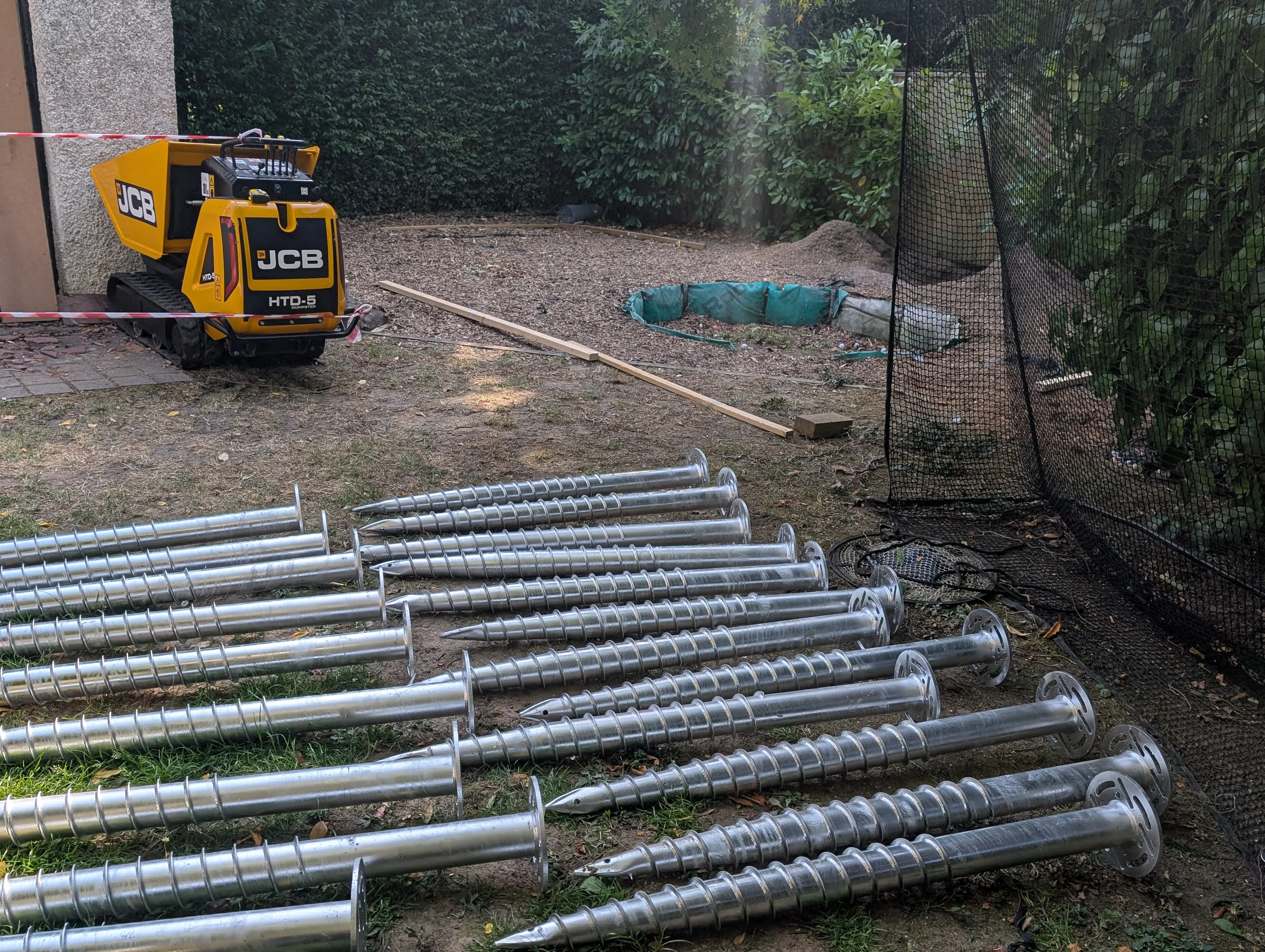 Large galvanised ground screws laid out beside installation equipment