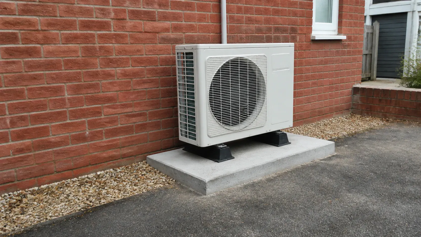 Air source heat pump outdoor unit standing on a neat ground-level base