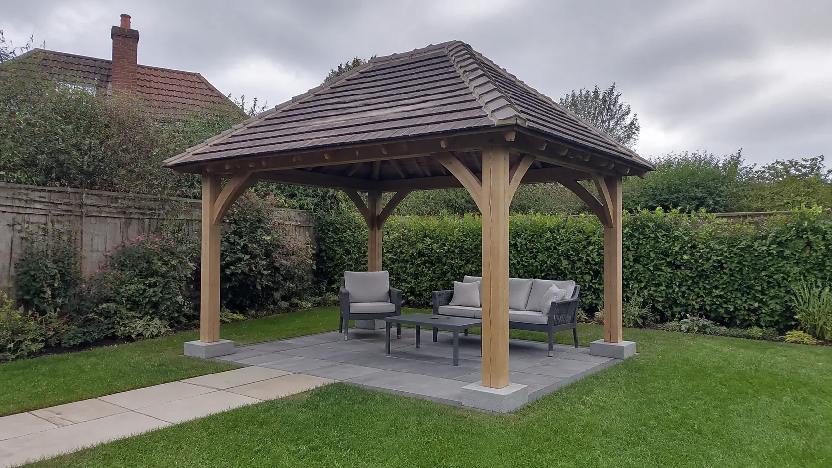 Open timber gazebo on a neat paved foundation in a British garden