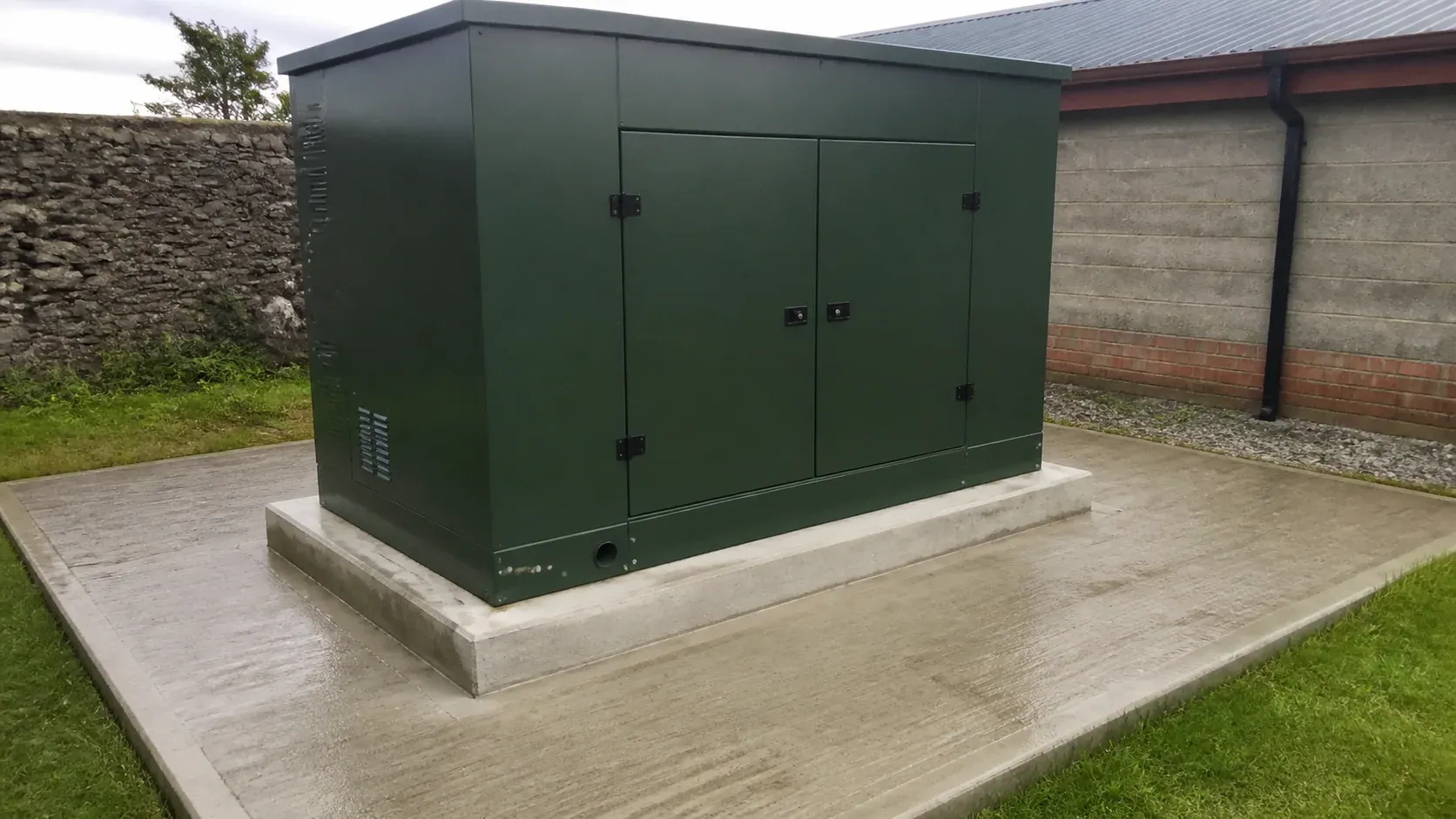 Enclosed standby generator secured on a concrete equipment pad