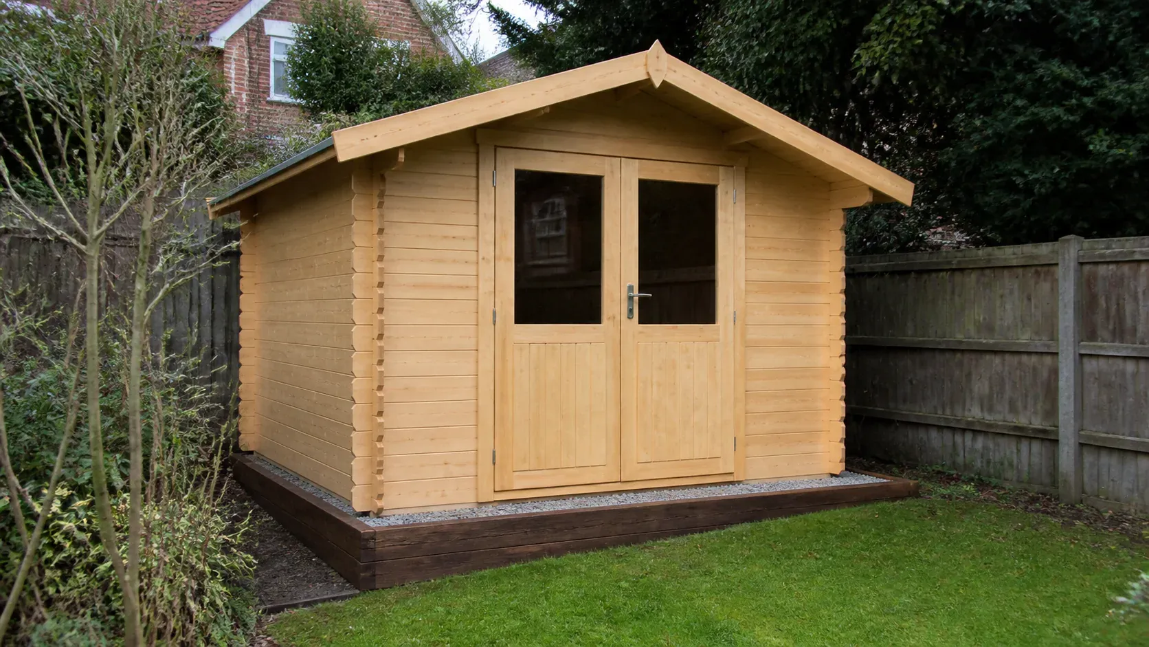 Garden log cabin on a neat level base beside a lawn