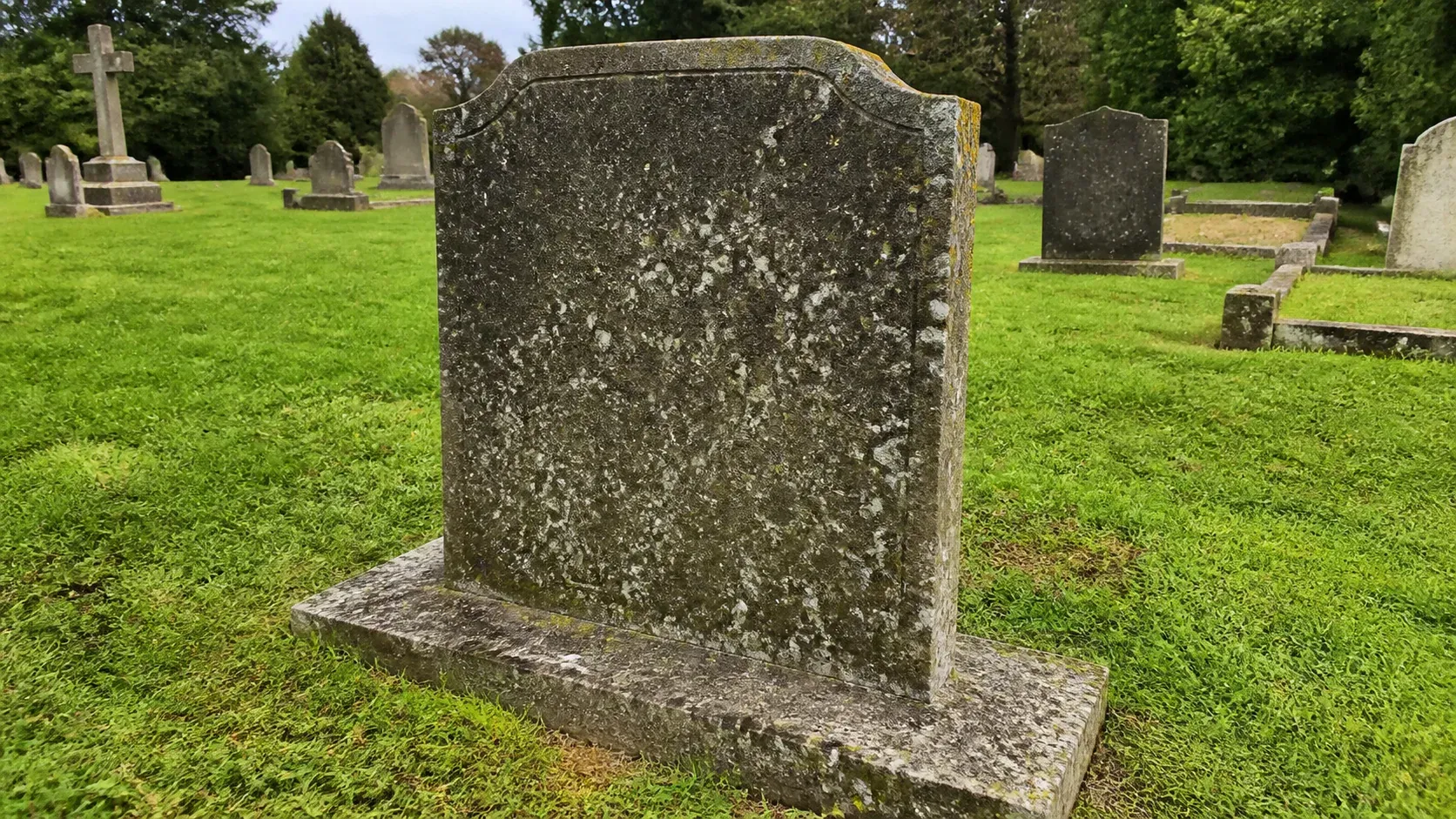Simple stone memorial standing level on a discreet foundation in a cemetery