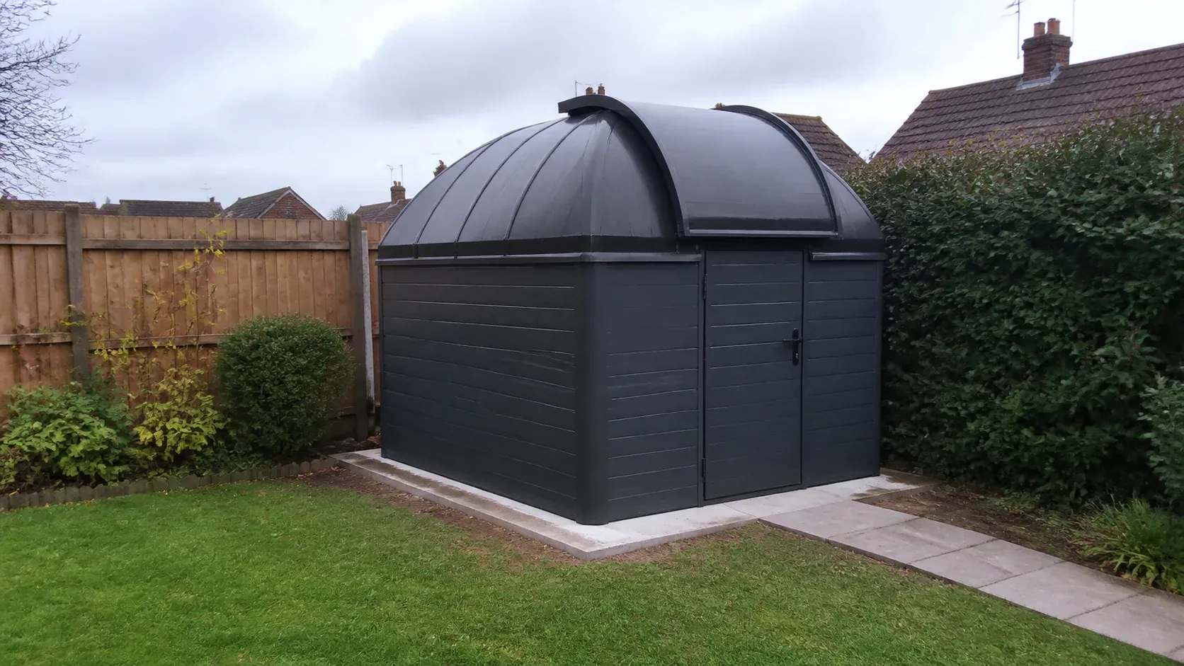 Small roll-off-roof astronomy observatory in a garden at dusk