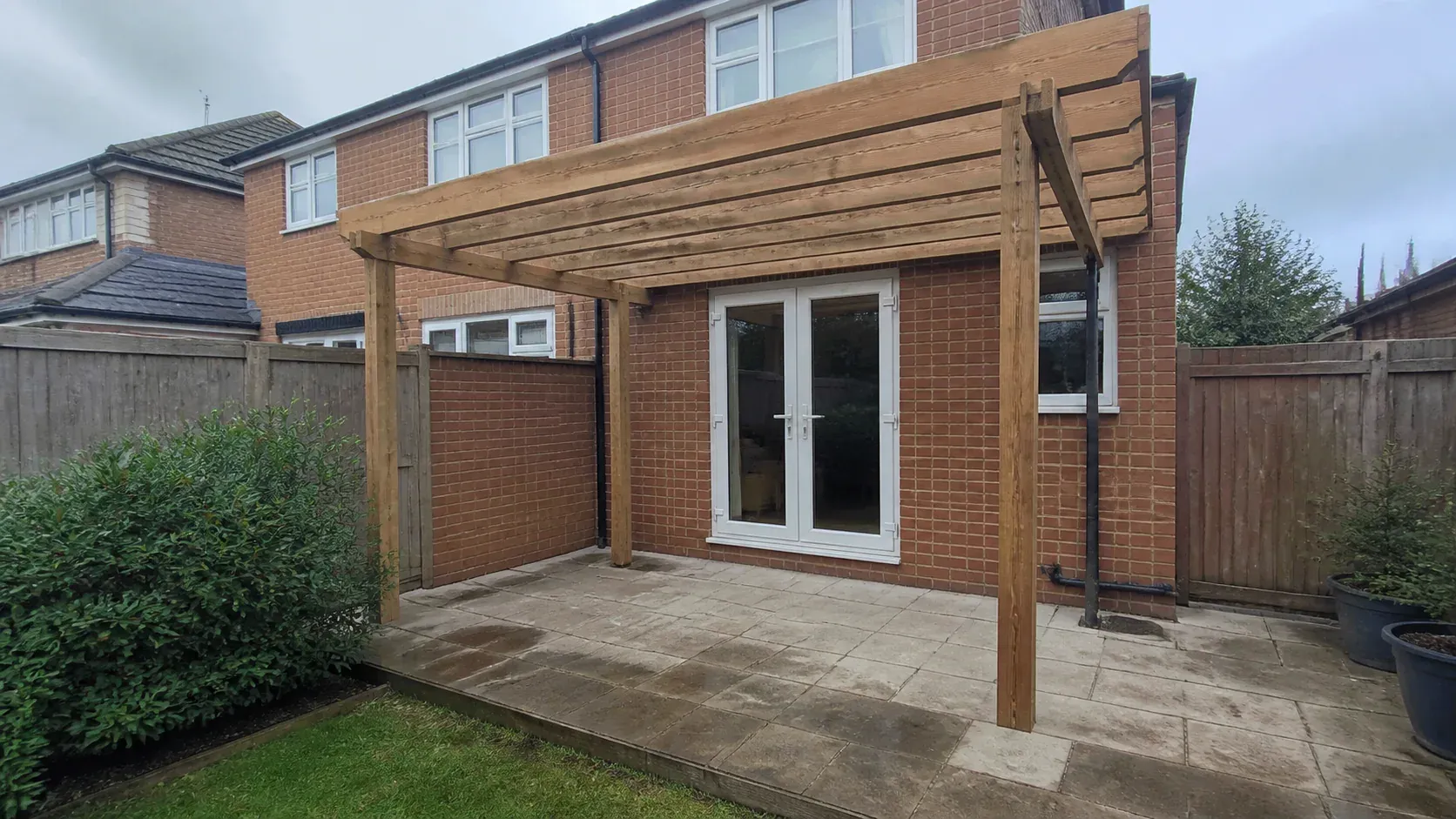 Modern pergola securely mounted beside a garden patio