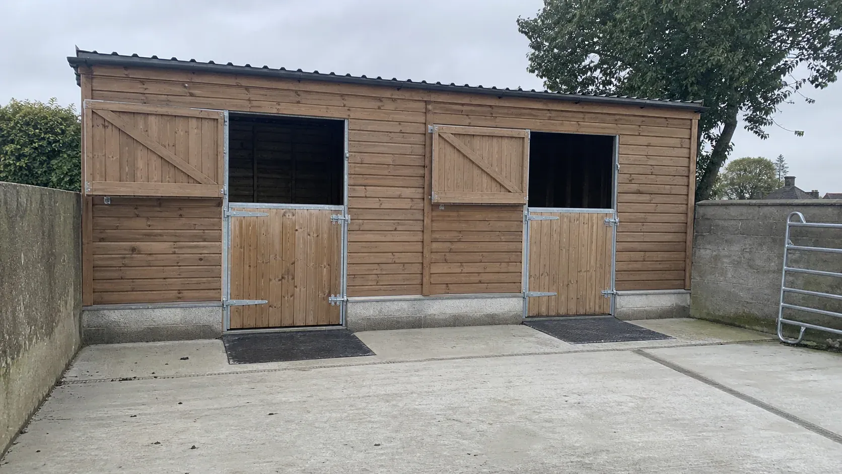 Timber stable block on a clean concrete base with open yard