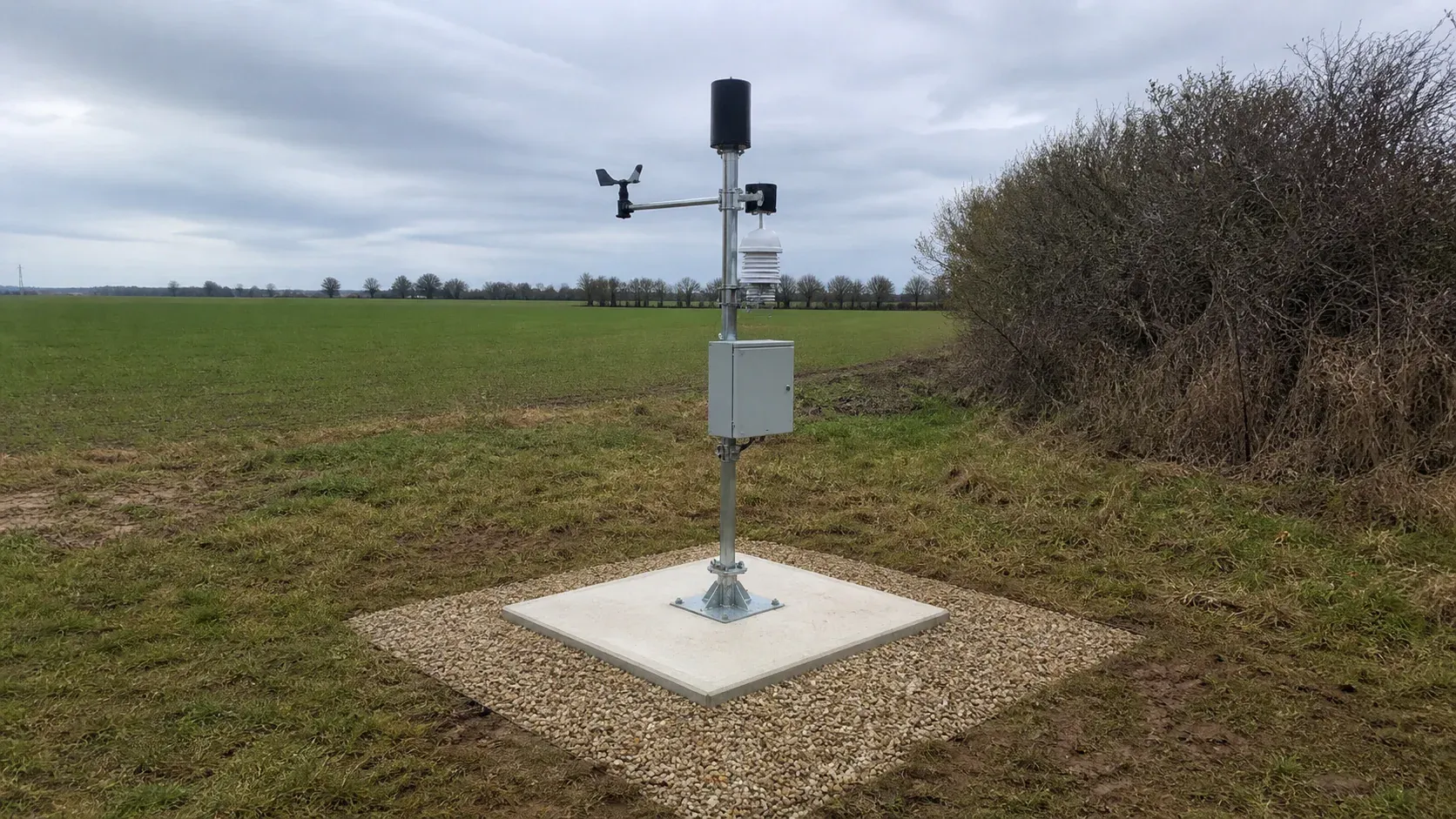Automatic weather station mast secured on a small concrete foundation